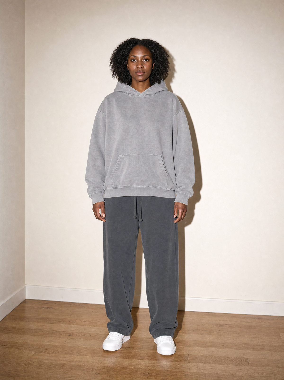Home & Away Boyfriend Hoodie in Gray, front view, worn against the apartment wall: 400 gsm heavyweight loopback cotton with a washed, individually dyed finish