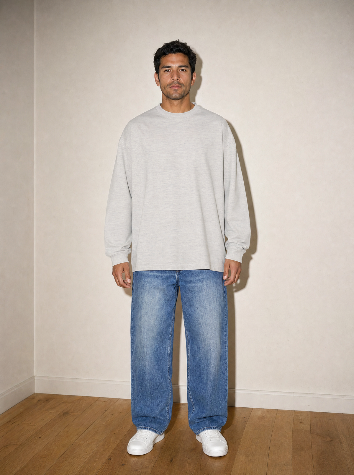 Home & Away Long Sleeve Tee in Oat Gray, front view, worn against the apartment wall: 305 gsm cotton jersey, about double a standard tee