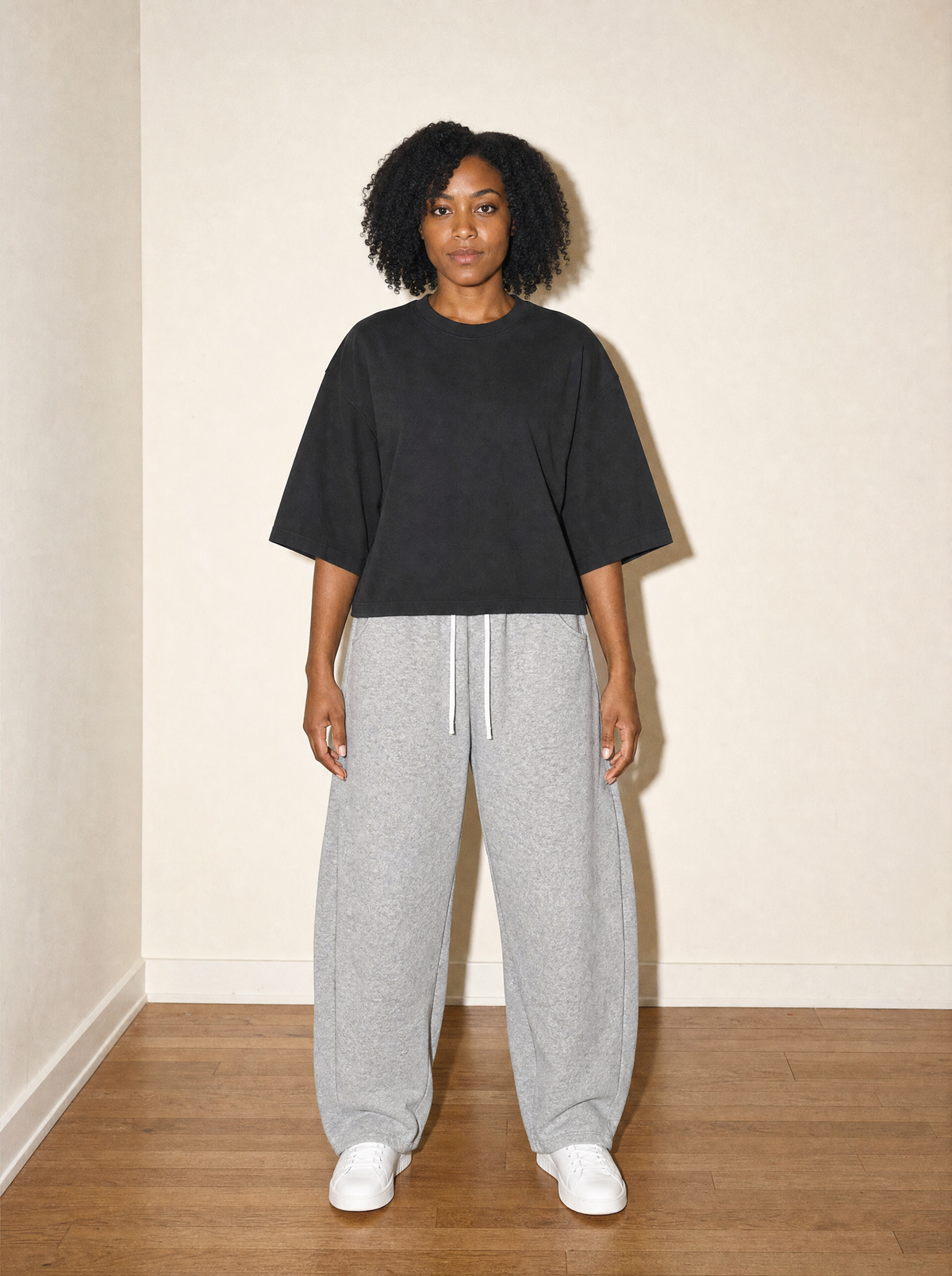 Home & Away Boxy Tee in Black, front view, worn against the apartment wall: 230 gsm cotton, washed soft, cut short and wide